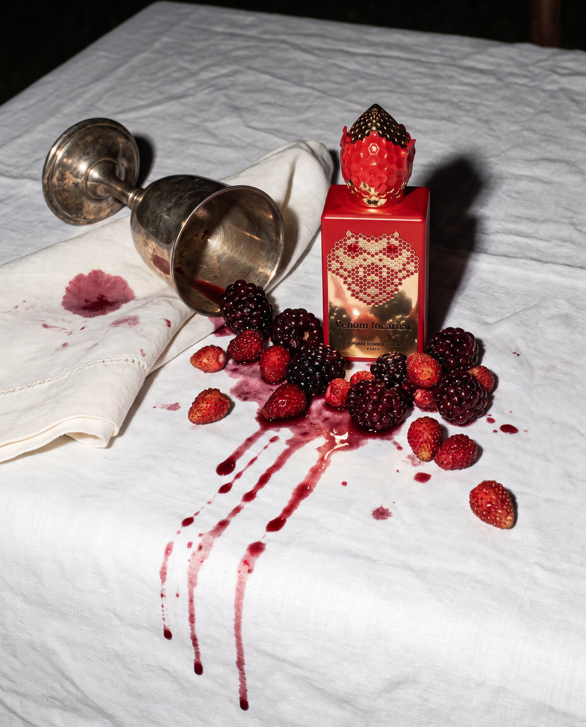 Venom Incarnat de Stéphane Humbert Lucas entre moras y fresas aplastadas sobre un mantel blanco